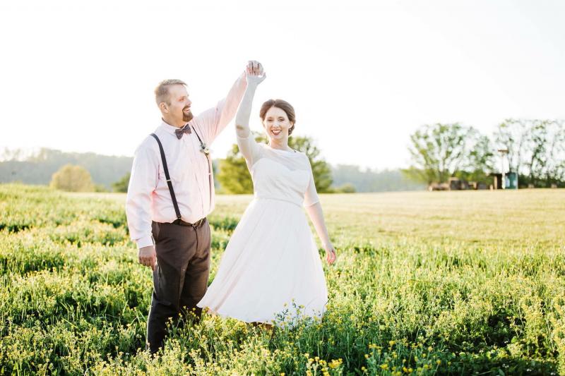 bride and groom dancing in a field 